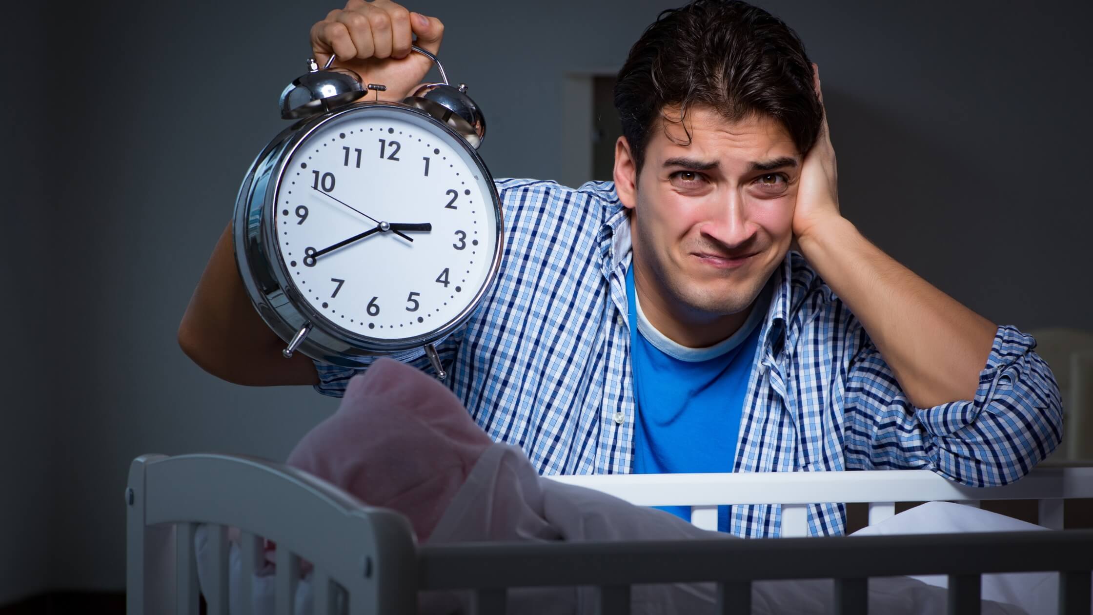 man holding clock over baby crib